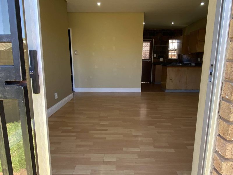 Open plan living area with laminate flooring and recessed lighting, flowing into a kitchen space. The interior is vacant and ready for personalization.