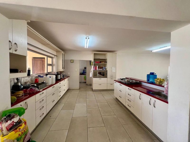 Spacious kitchen featuring extensive built-in cabinetry, laminate countertops, double sink, and built-in oven, offering a functional layout with ample storage space.