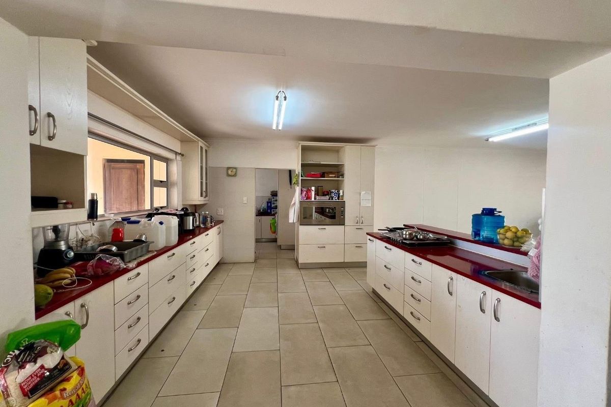 Spacious kitchen featuring extensive built-in cabinetry, laminate countertops, double sink, and built-in oven, offering a functional layout with ample storage space.