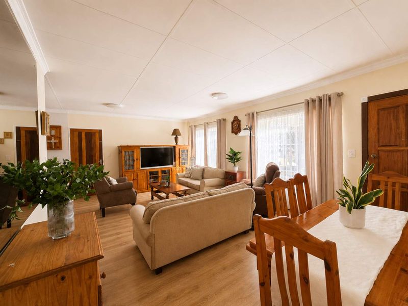 Spacious open-plan living and dining area featuring light-toned laminate flooring, neutral walls, and classic wooden door finishes.