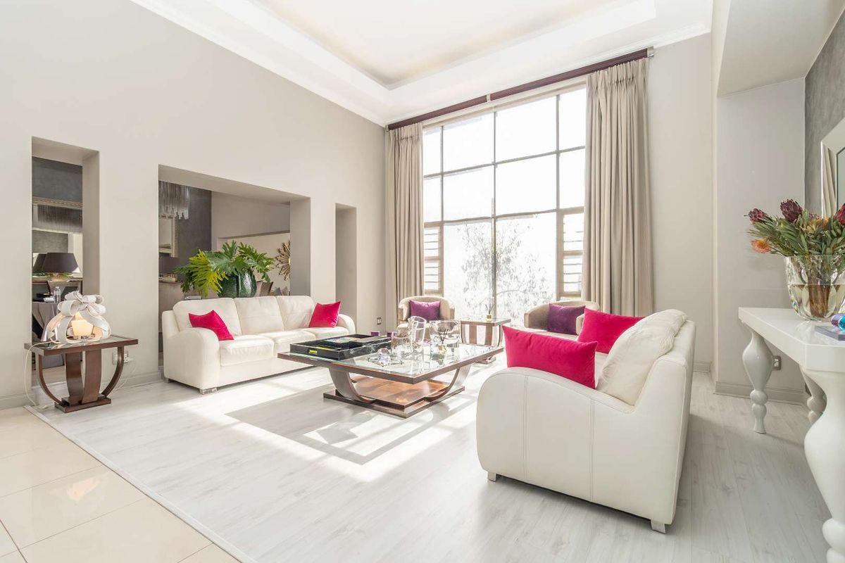 Spacious living room featuring high ceilings, large floor-to-ceiling windows, and elegant tiled flooring, creating a bright and airy atmosphere.