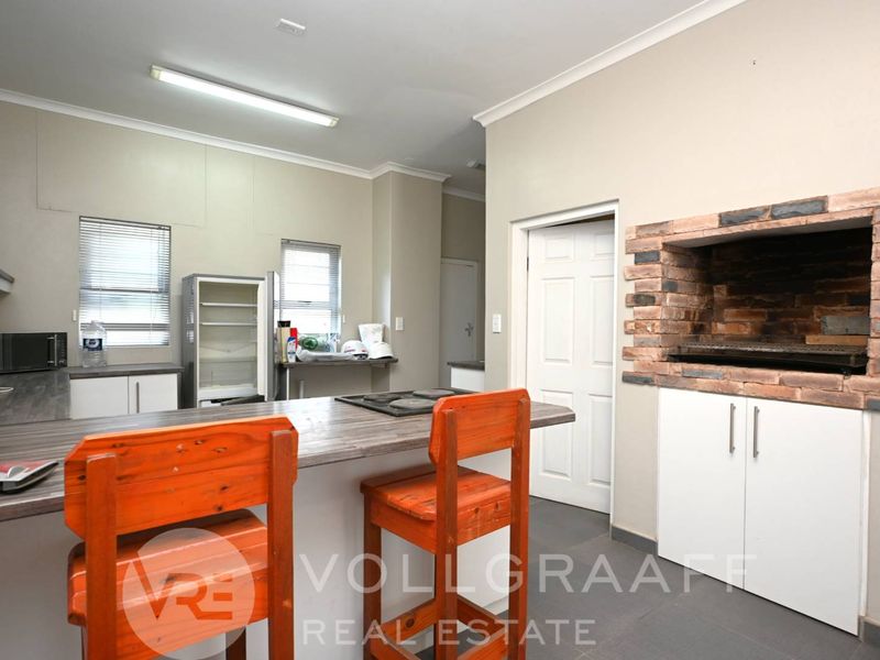Open plan kitchen and entertainment area featuring a built-in brick braai, kitchen island with hob, and neutral finishes.
