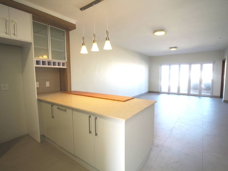 Spacious open-plan living area featuring a modern kitchen with stone countertops, pendant lighting, and large sliding doors leading to an outdoor space.