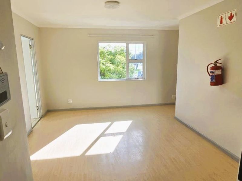 An open-plan living and kitchen area featuring neutral walls, vinyl flooring, and a built-in stove, offering a bright and functional blank canvas.