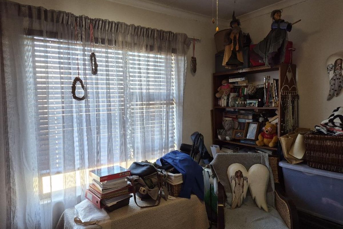 A bedroom featuring a large window with venetian blinds and curtain rod, showing signs of wear on the ceiling.