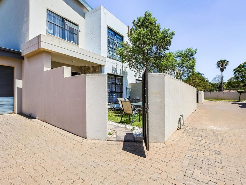 Front exterior view of the townhouse featuring a paved driveway, private gated entrance, and garage access.