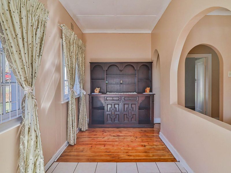 A bright hallway featuring a mix of hardwood and tiled flooring, accented by a decorative archway leading to adjacent living spaces.