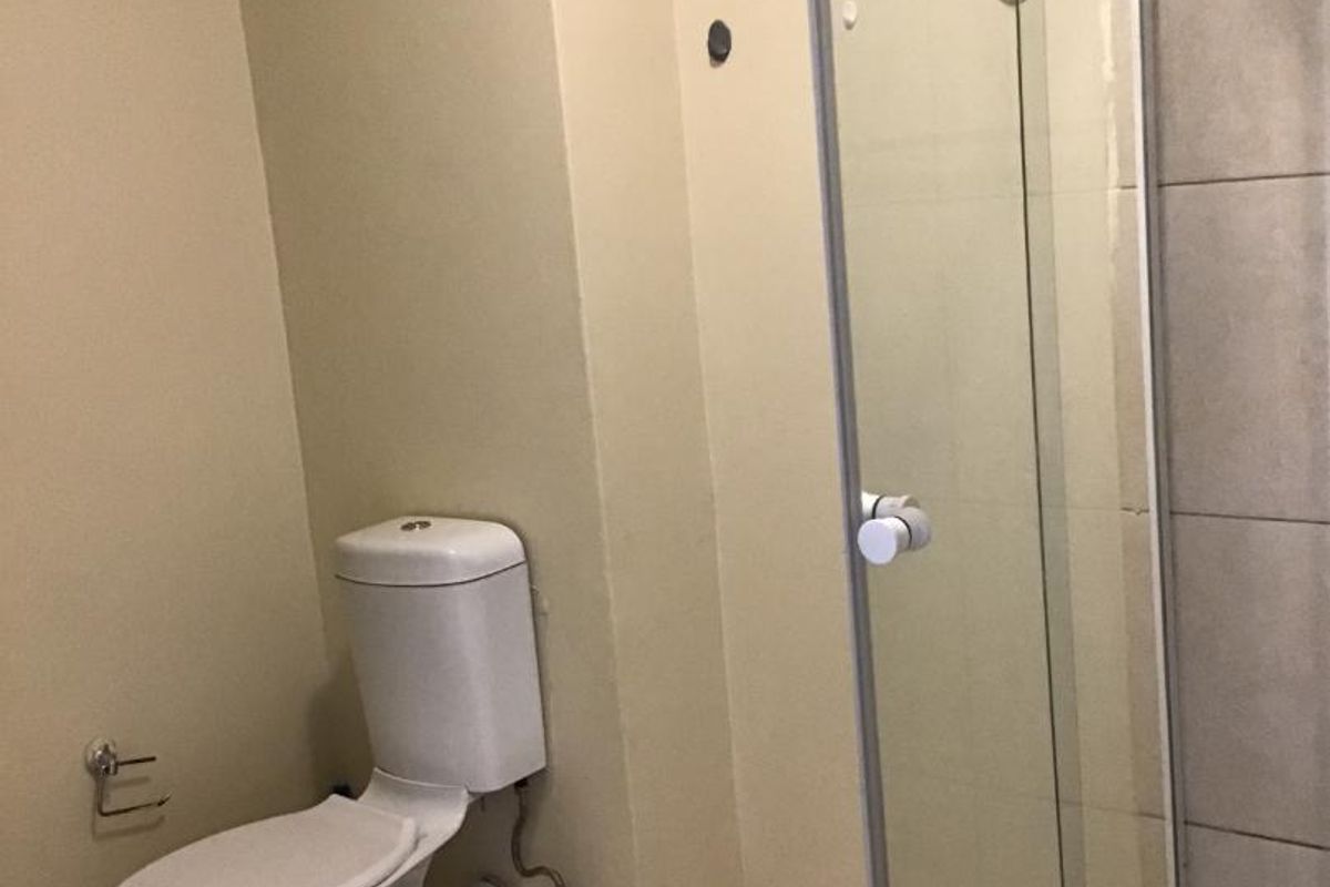 A functional bathroom featuring a standard toilet and a glass-enclosed shower with tiled finishes.