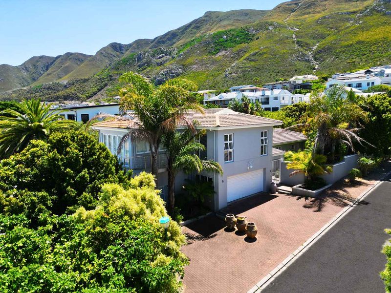 Elevated view of a well-maintained double-story residence featuring a tiled roof, paved driveway, and double garage, set against a scenic mountain backdrop.