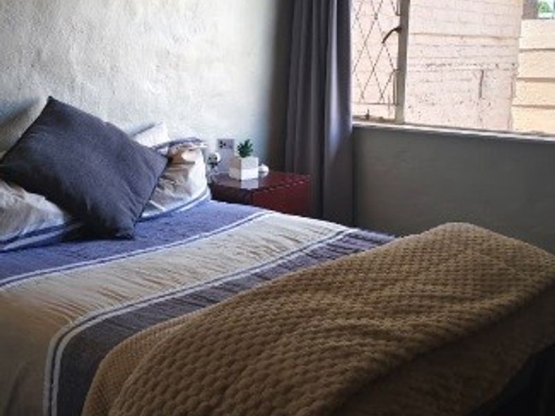 A bedroom featuring tiled flooring and a leaded glass window with curtain tracks, offering a functional space with neutral wall finishes.