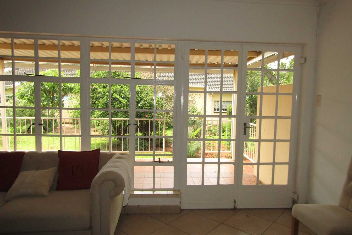 Bright living area featuring large white-framed French doors and windows that provide direct access to the garden and patio.