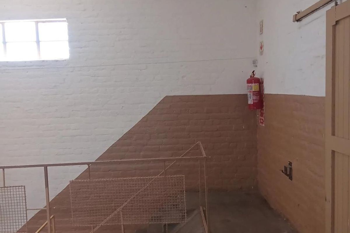 Industrial style hallway featuring exposed brick walls, concrete flooring, and a metal balustrade, providing a functional and utilitarian transition space.