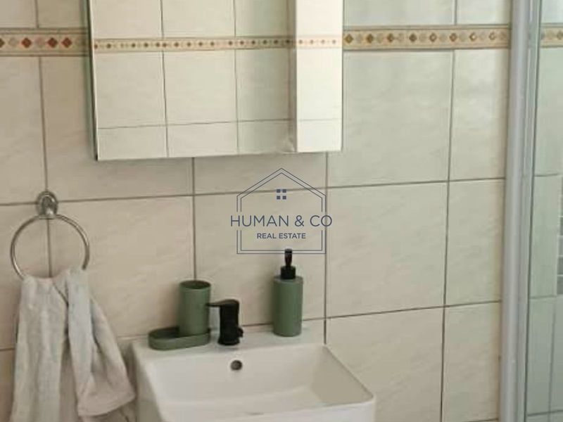 A functional bathroom featuring tiled walls, a wall-mounted basin, and a mirror cabinet, providing essential fixtures for daily use.