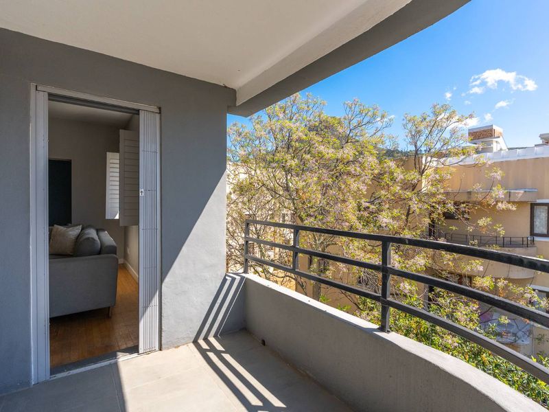 A private balcony featuring tiled flooring and a metal balustrade, offering an outdoor space accessible from the living area.
