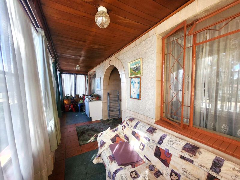 A covered patio area featuring a timber ceiling, tiled flooring, and an arched entryway, providing a functional transition space between indoor and outdoor areas.