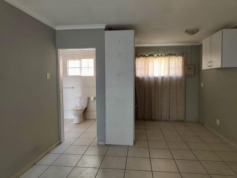 Open plan living area featuring tiled flooring and an adjoining bathroom, offering a blank canvas for renovation and interior design updates.