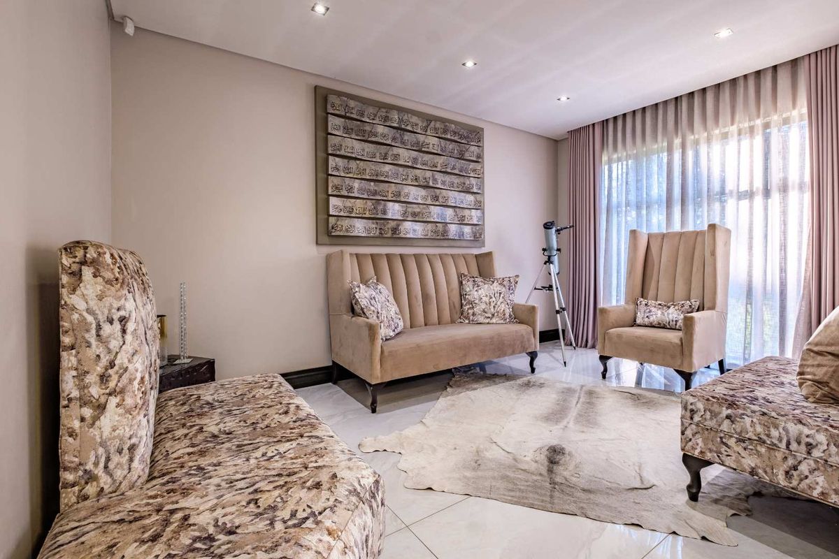 A well-maintained living room featuring polished porcelain floor tiles, recessed downlighting, and floor-to-ceiling curtain tracks.