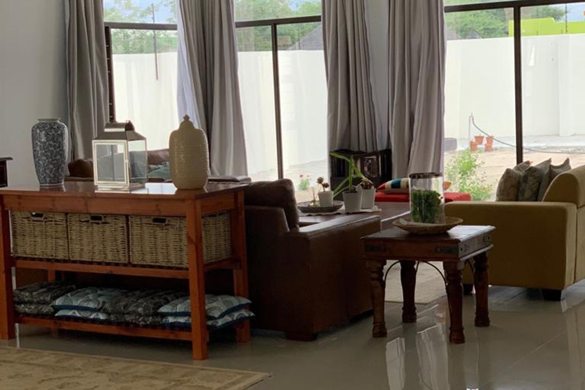 Spacious living area featuring large floor-to-ceiling windows with curtain tracks, polished tile flooring, and recessed ceiling lighting.