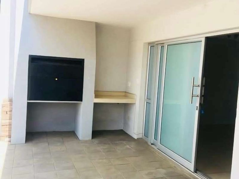 Covered patio area featuring a built-in braai, tiled flooring, and sliding glass doors providing access to the interior living space.