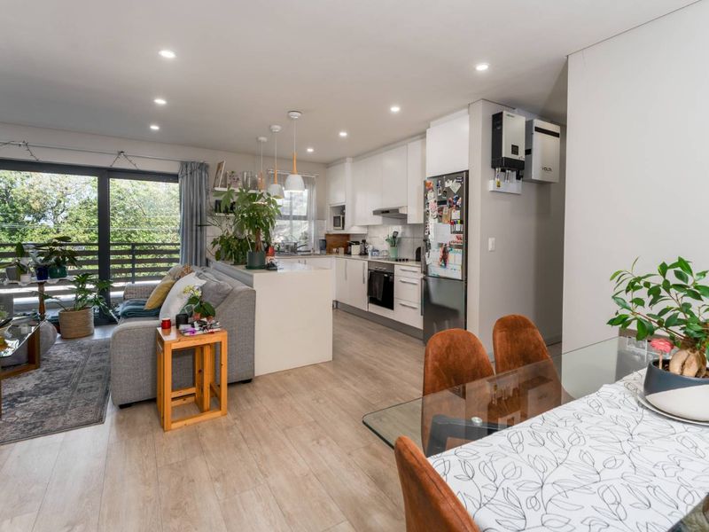 Modern open-plan living area featuring a sleek kitchen with built-in appliances, recessed lighting, and seamless access to a private balcony.