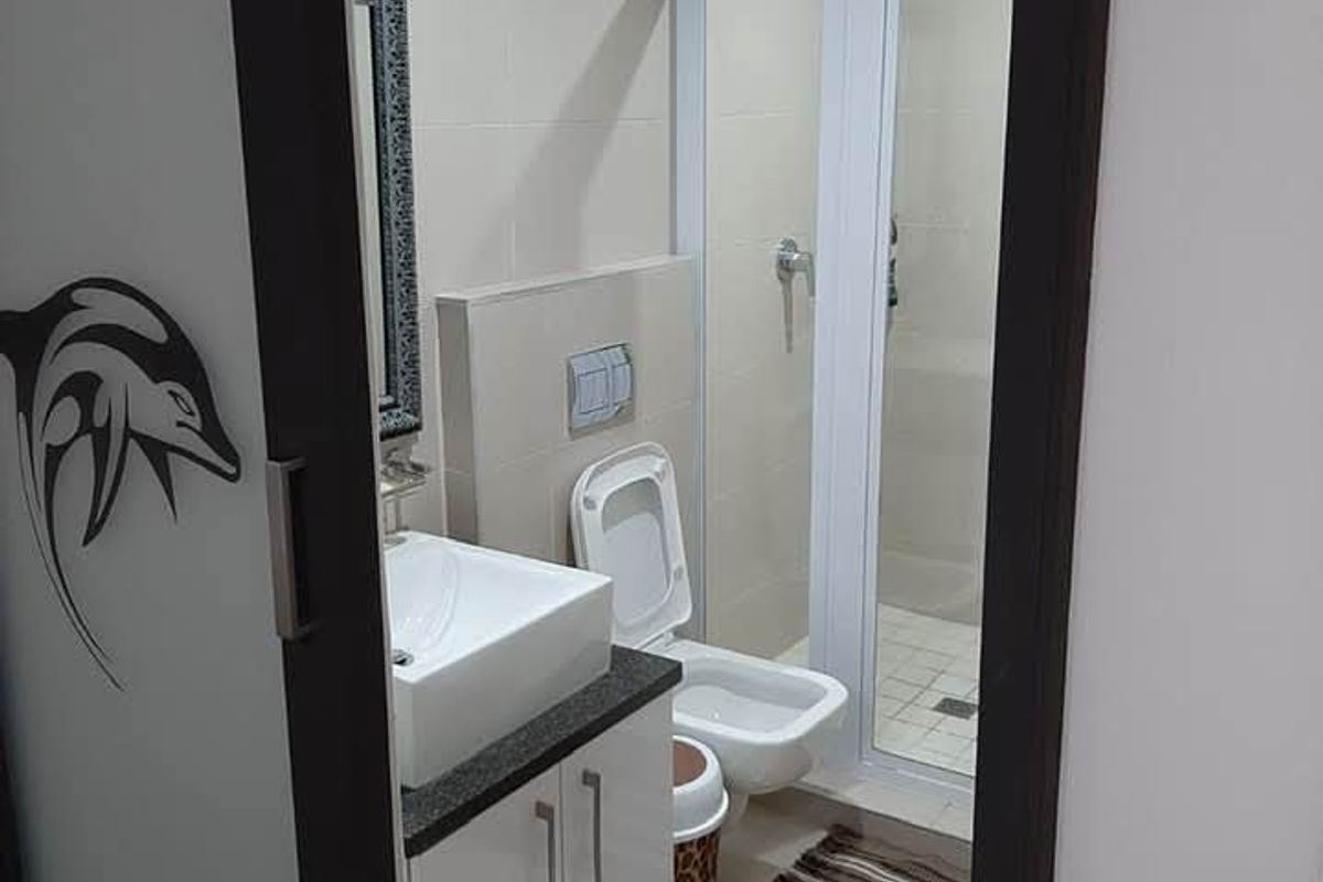 A modern bathroom featuring a glass shower enclosure, wall-hung toilet, and a sleek vanity with a vessel sink.