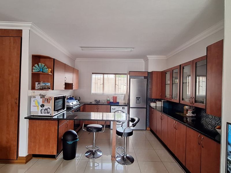 A functional kitchen featuring extensive wooden cabinetry, granite countertops, tiled flooring, and a breakfast bar area with integrated storage.