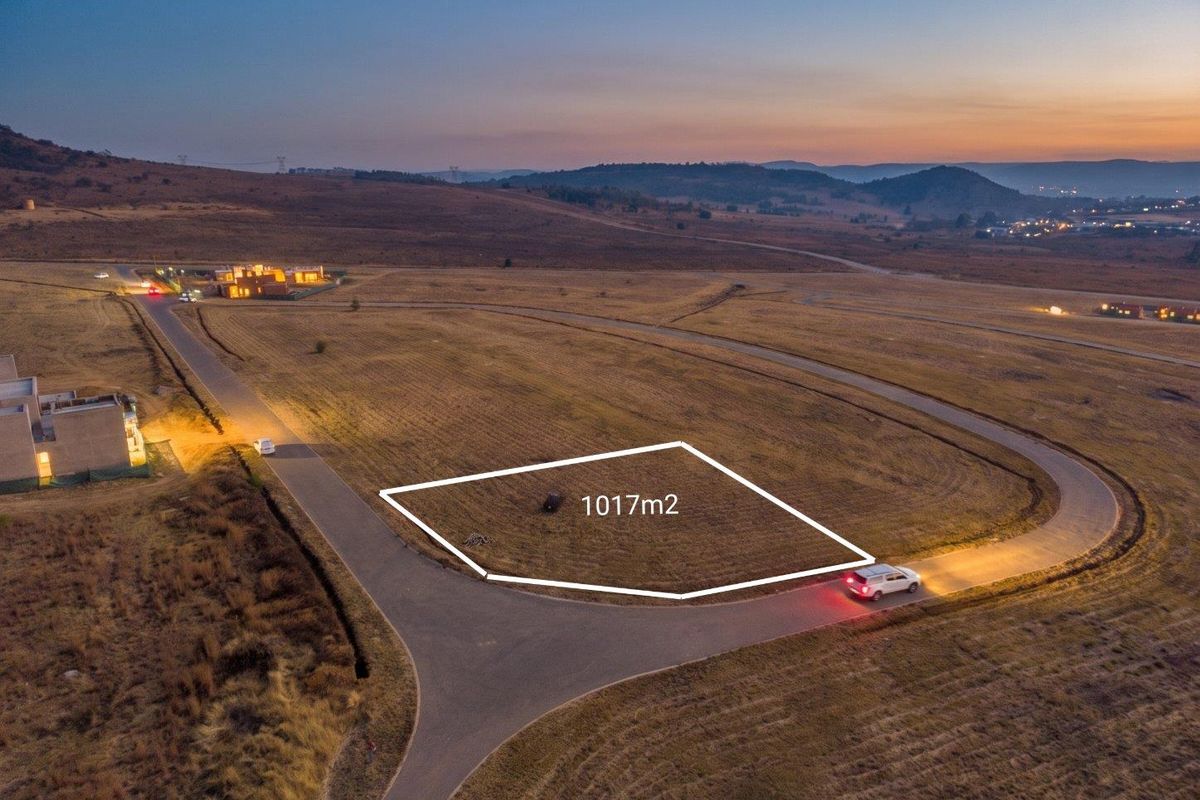Aerial view of a 1017m2 vacant residential plot situated in a developed estate with paved road access and scenic landscape views.