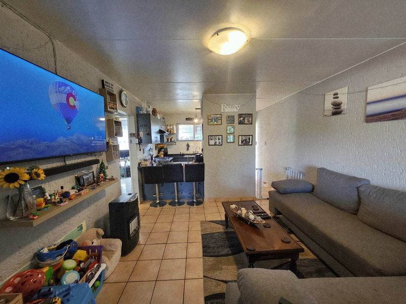 Open-plan living area featuring ceramic floor tiles and a functional kitchen with a breakfast bar, creating a combined space for dining and relaxation.