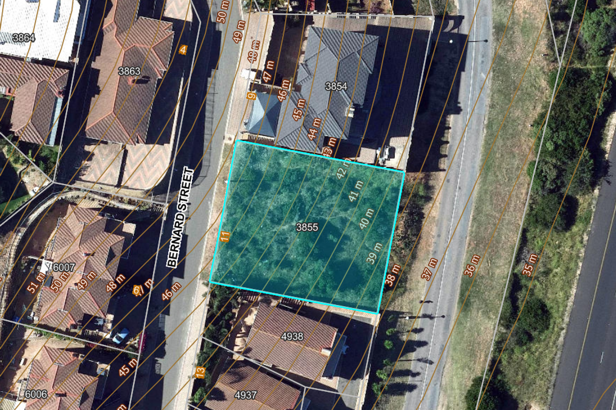 An aerial view of a vacant residential plot highlighted with topographical contour lines, situated within an established suburban street layout.