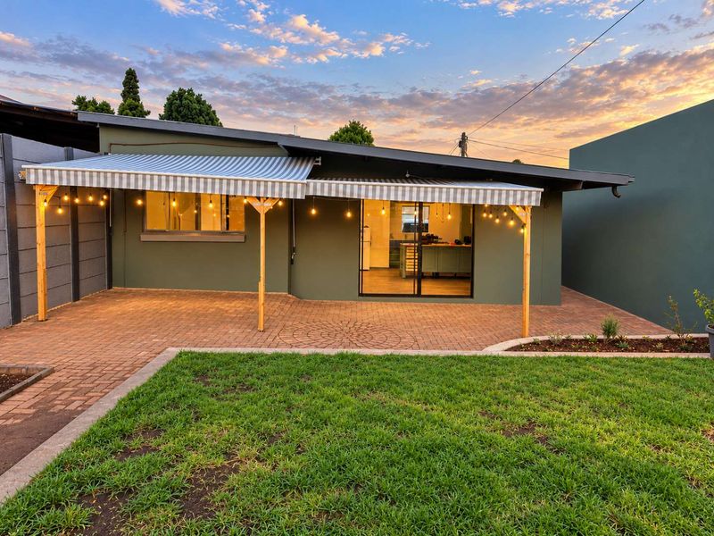 A well-maintained rear exterior featuring a paved patio area, retractable awning, and direct access to the interior through sliding glass doors.