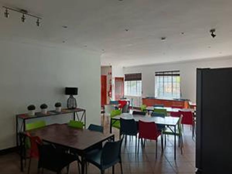 Spacious open-plan living area featuring tiled flooring, recessed lighting, and large windows, offering a versatile layout suitable for dining or communal use.
