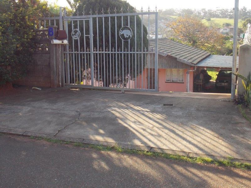 Front view of the property featuring a metal security gate, concrete driveway, and a carport attached to the main house structure.