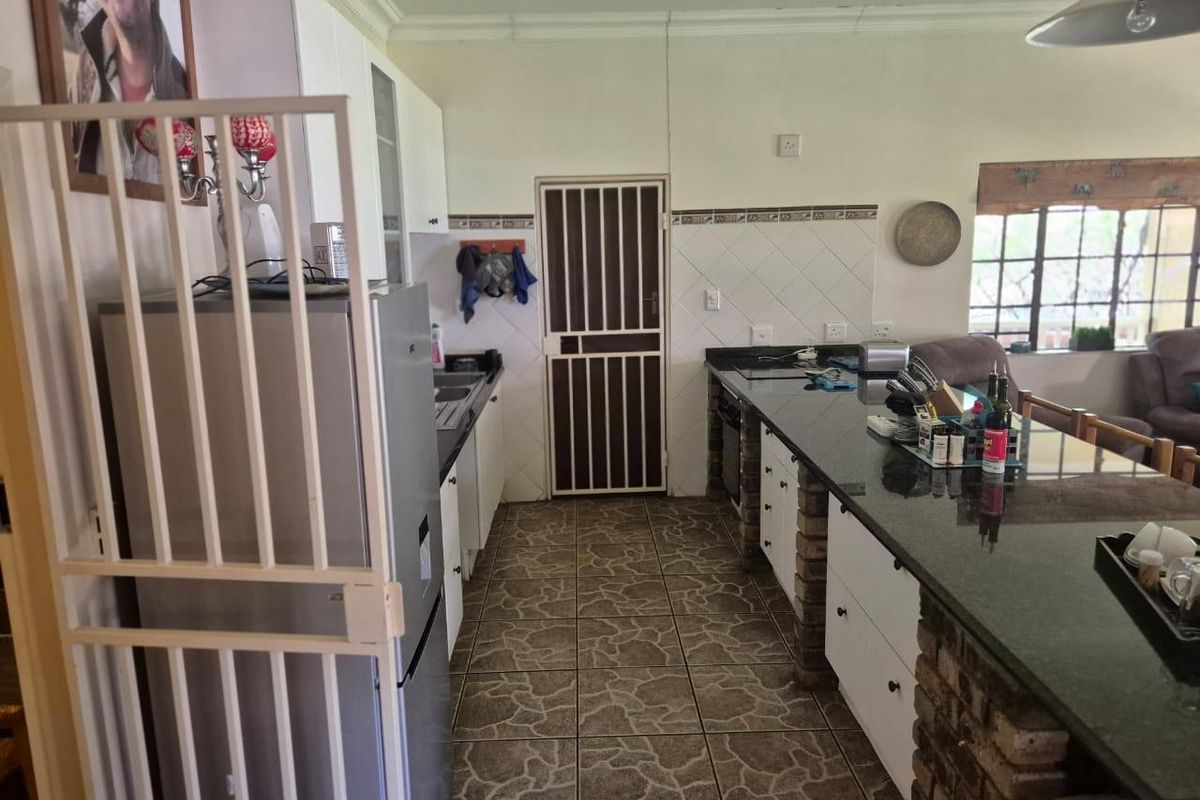 Kitchen featuring a long granite breakfast bar, brick base cabinetry, tiled flooring, and a security gate leading to the exterior.