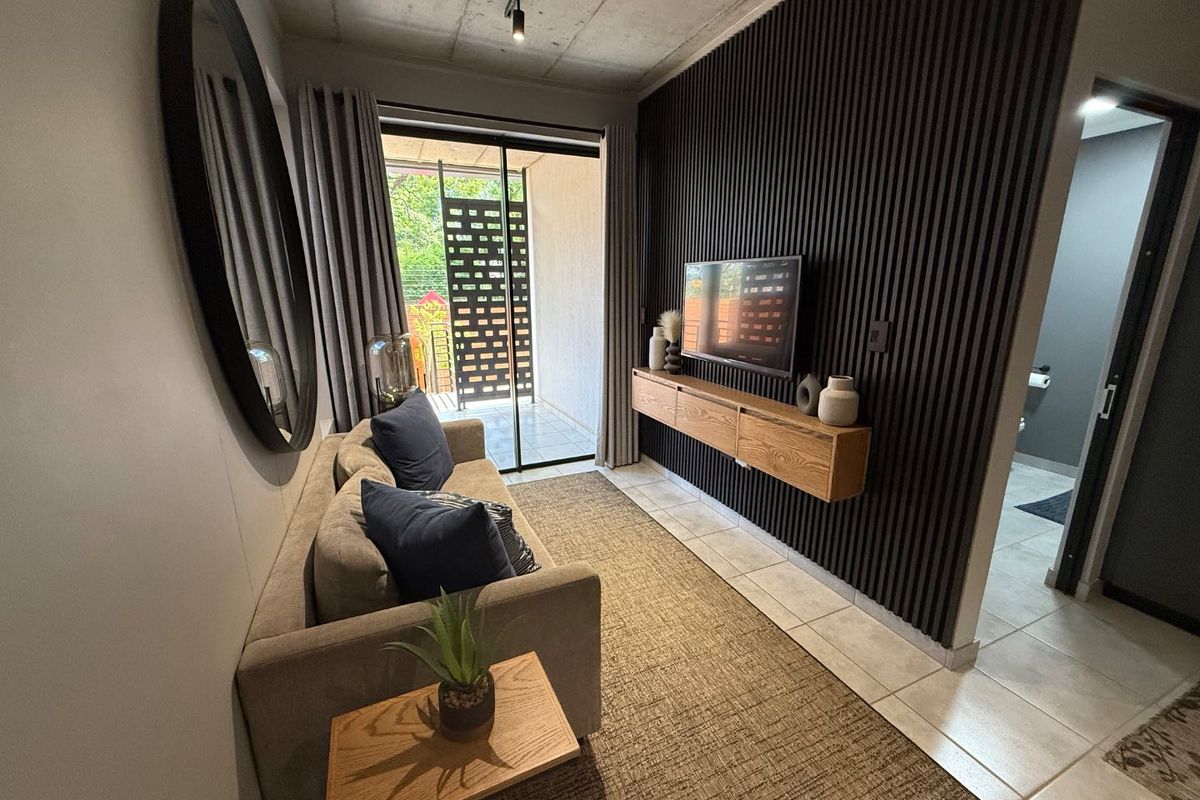 Modern living room featuring an exposed concrete ceiling, a stylish slatted timber feature wall with a floating console, and direct access to a private balcony.