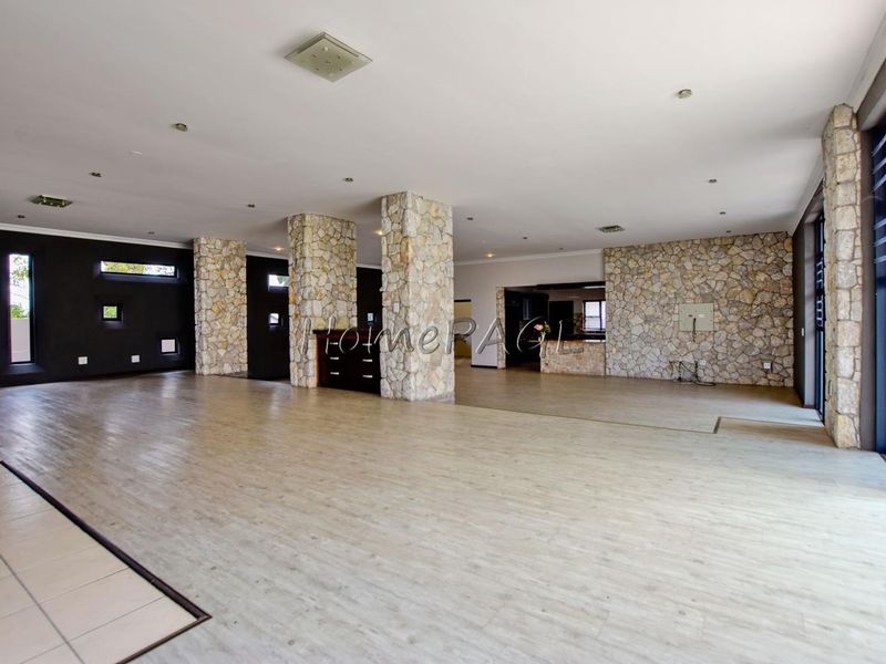 Spacious open-plan living area featuring striking stone-clad columns, a stone feature wall, and large sliding glass doors providing ample natural light.