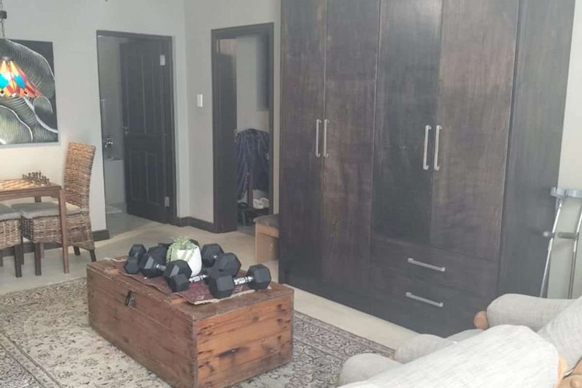 A bedroom featuring built-in dark wood cabinetry, a ceiling fan, and access to an adjoining bathroom.