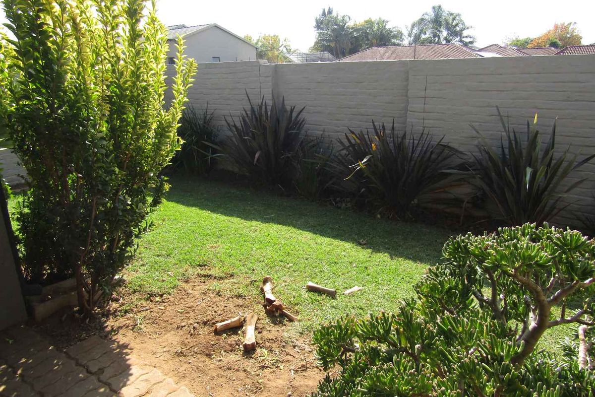 A private rear garden featuring a lawn area, established shrubs, and a solid boundary wall, providing a secure outdoor space.