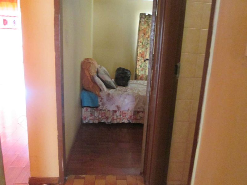 A view through a doorway into a bedroom featuring laminate flooring and dated wall finishes, requiring cosmetic updates.