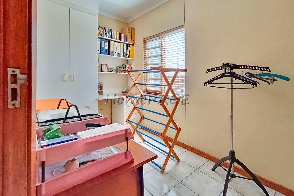 A functional bedroom or study featuring built-in cupboards, tiled flooring, and a built-in desk area with shelving.