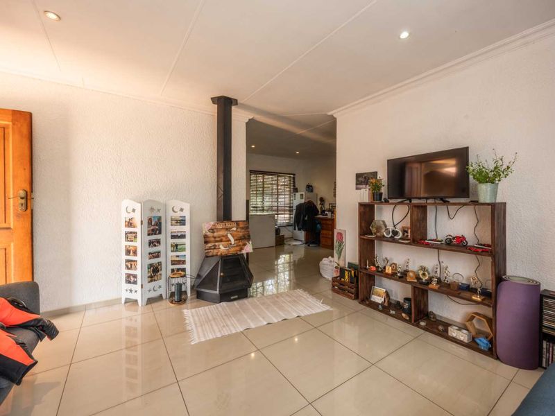 A spacious living room featuring tiled flooring, a central freestanding fireplace, and recessed downlighting, offering a comfortable and functional living space.