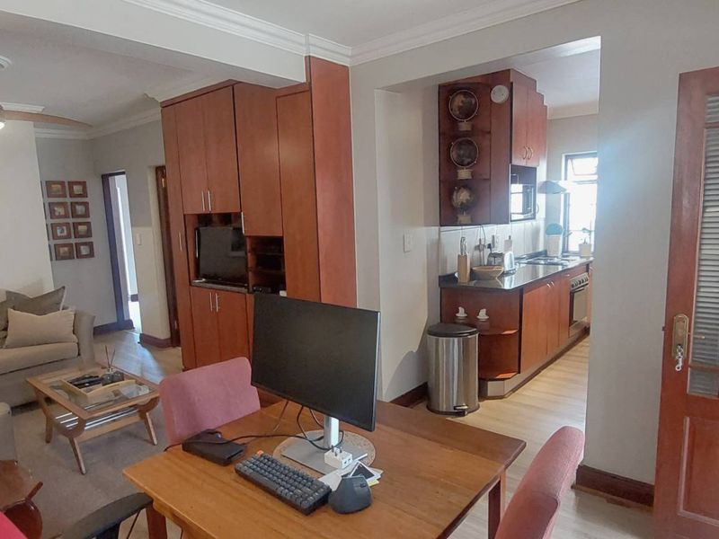 Open-plan living and dining area featuring built-in cabinetry and a functional kitchen with integrated appliances, creating a cohesive and practical living space.