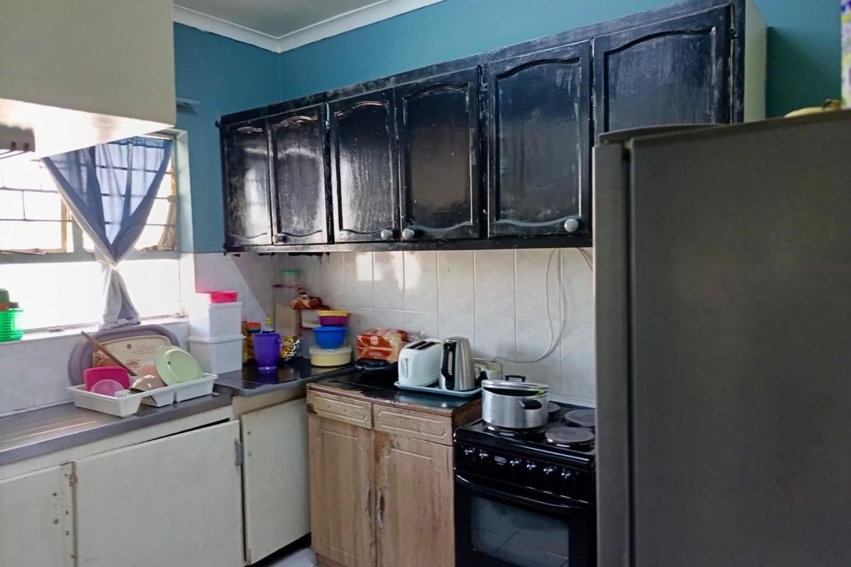 A functional kitchen featuring a mix of dark and wood-toned cabinetry, tiled backsplash, and a freestanding stove, offering potential for modernization.