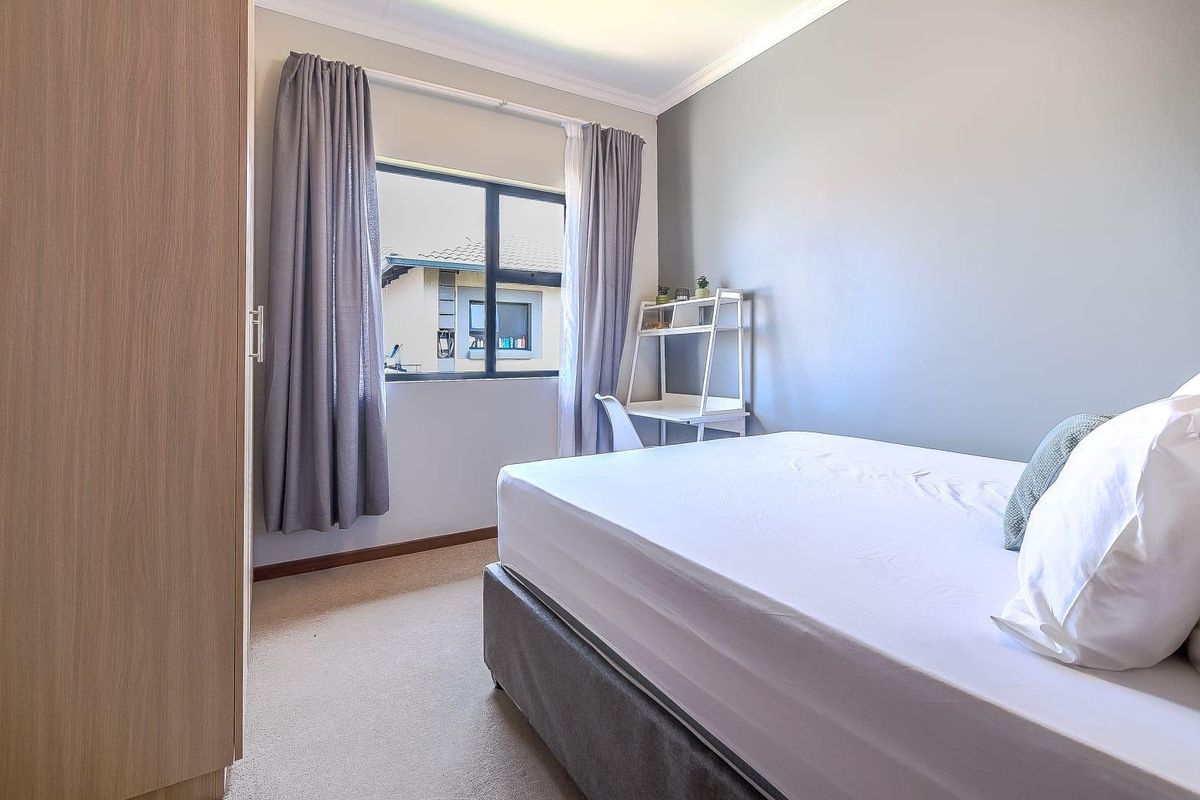 A well-maintained bedroom featuring neutral wall tones, carpeted flooring, and a built-in wardrobe, offering a comfortable and functional living space.