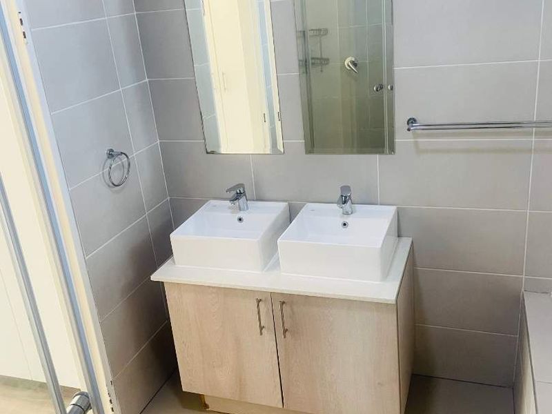 Modern bathroom featuring a double vanity with ceramic basins, tiled walls and flooring, and wall-mounted mirrors.