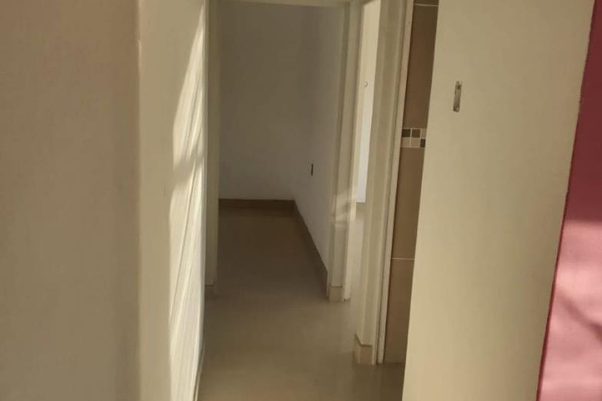 A neutral-toned interior hallway featuring tiled flooring and clean architectural lines, providing access to adjacent rooms within the townhouse.