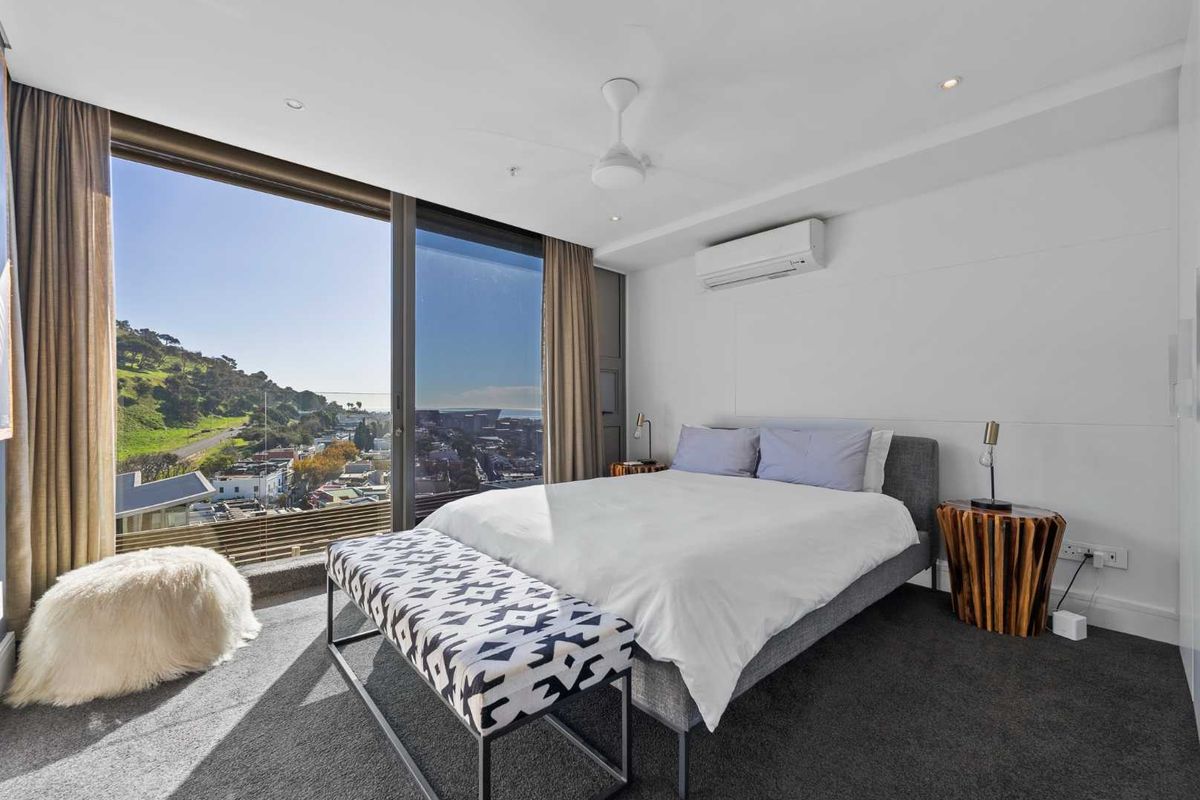 Modern bedroom featuring floor-to-ceiling windows with expansive views, wall-mounted air conditioning unit, and recessed ceiling lighting.