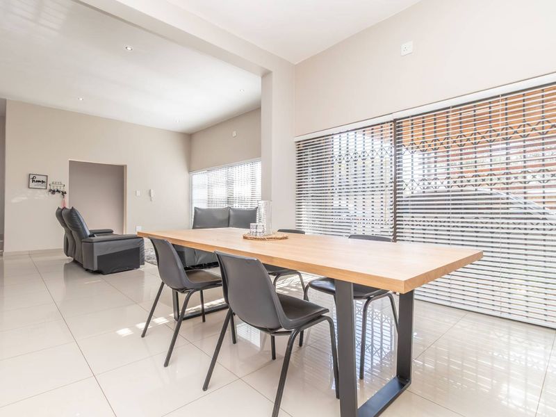 Spacious open-plan living and dining area featuring neutral tiled flooring, recessed lighting, and large sliding doors with integrated security shutters.