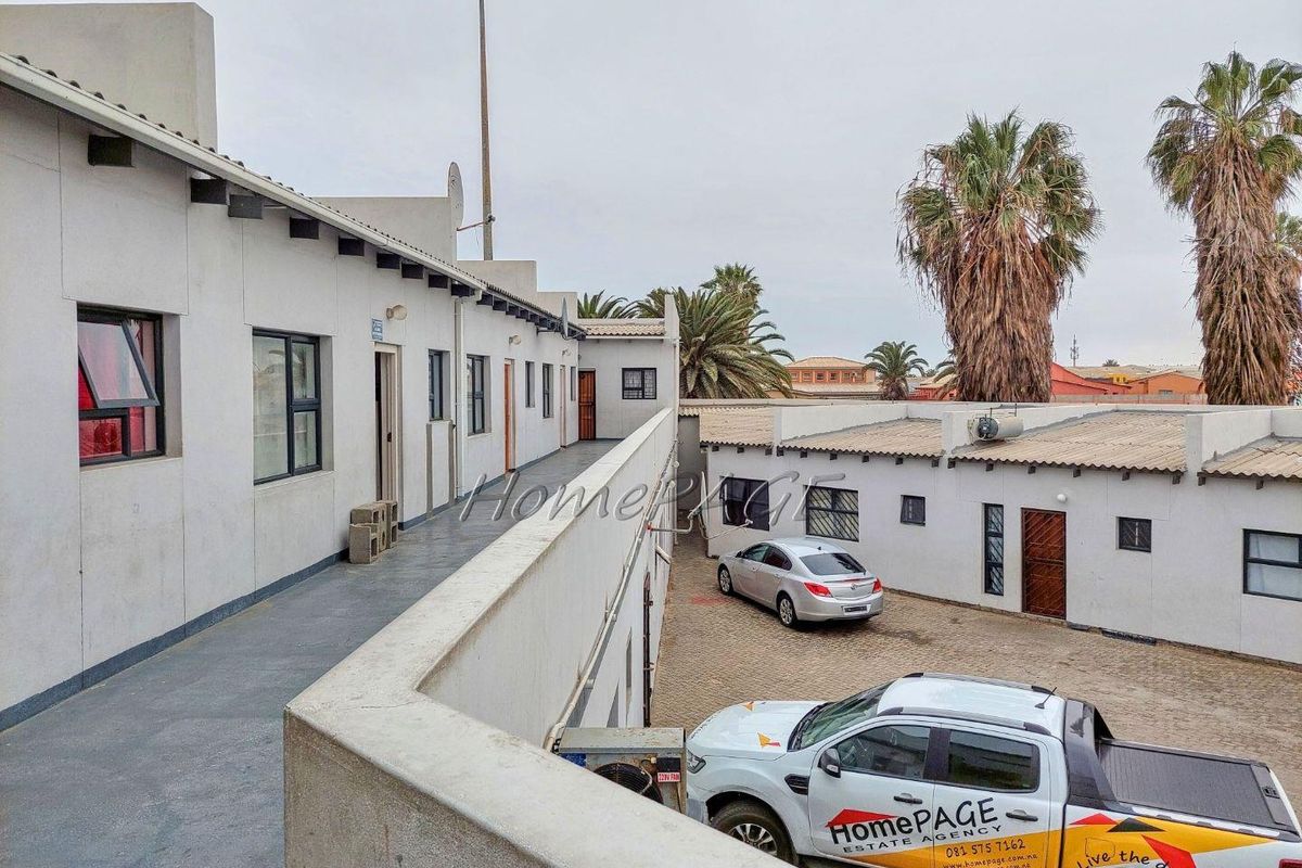Exterior view of an apartment complex featuring a paved courtyard, walkways, and multiple unit entrances.