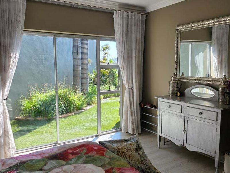 A bright bedroom featuring laminate flooring, recessed lighting, and a large sliding glass door providing direct access to the garden.