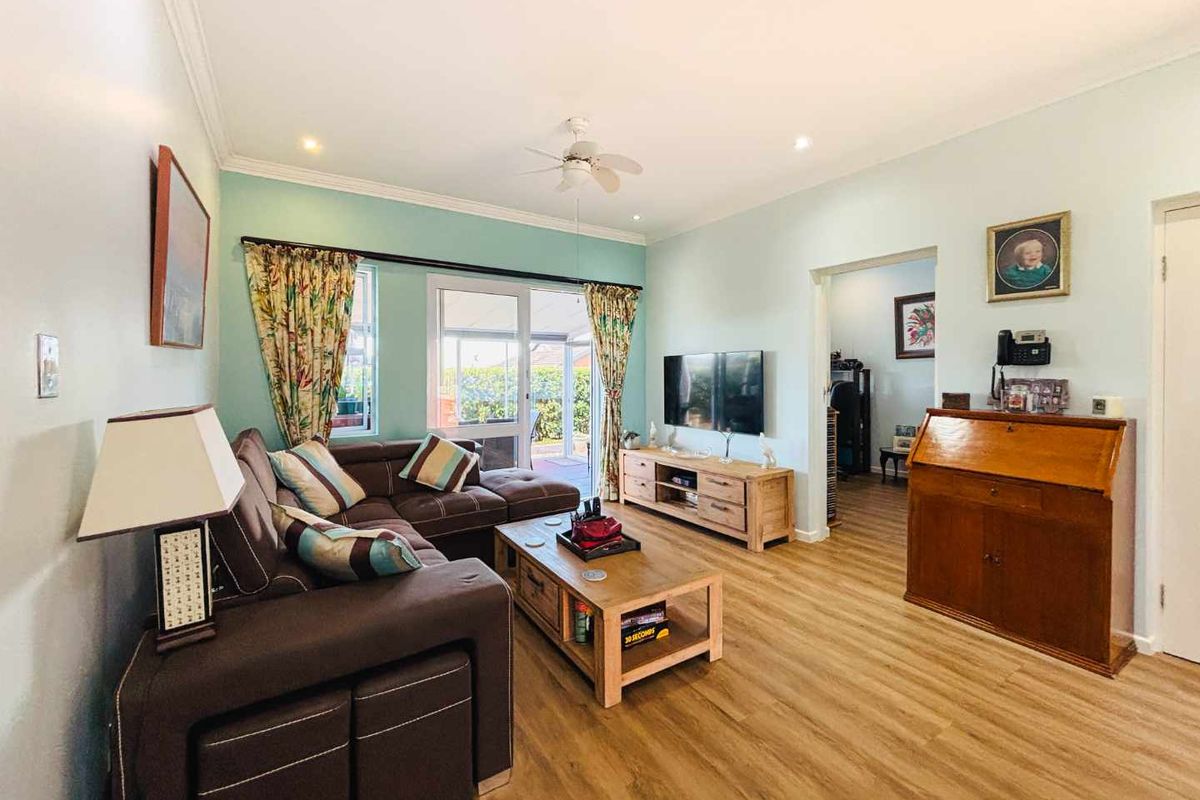 A well-maintained living room featuring laminate flooring, recessed lighting, a ceiling fan, and sliding glass doors leading to an outdoor area.